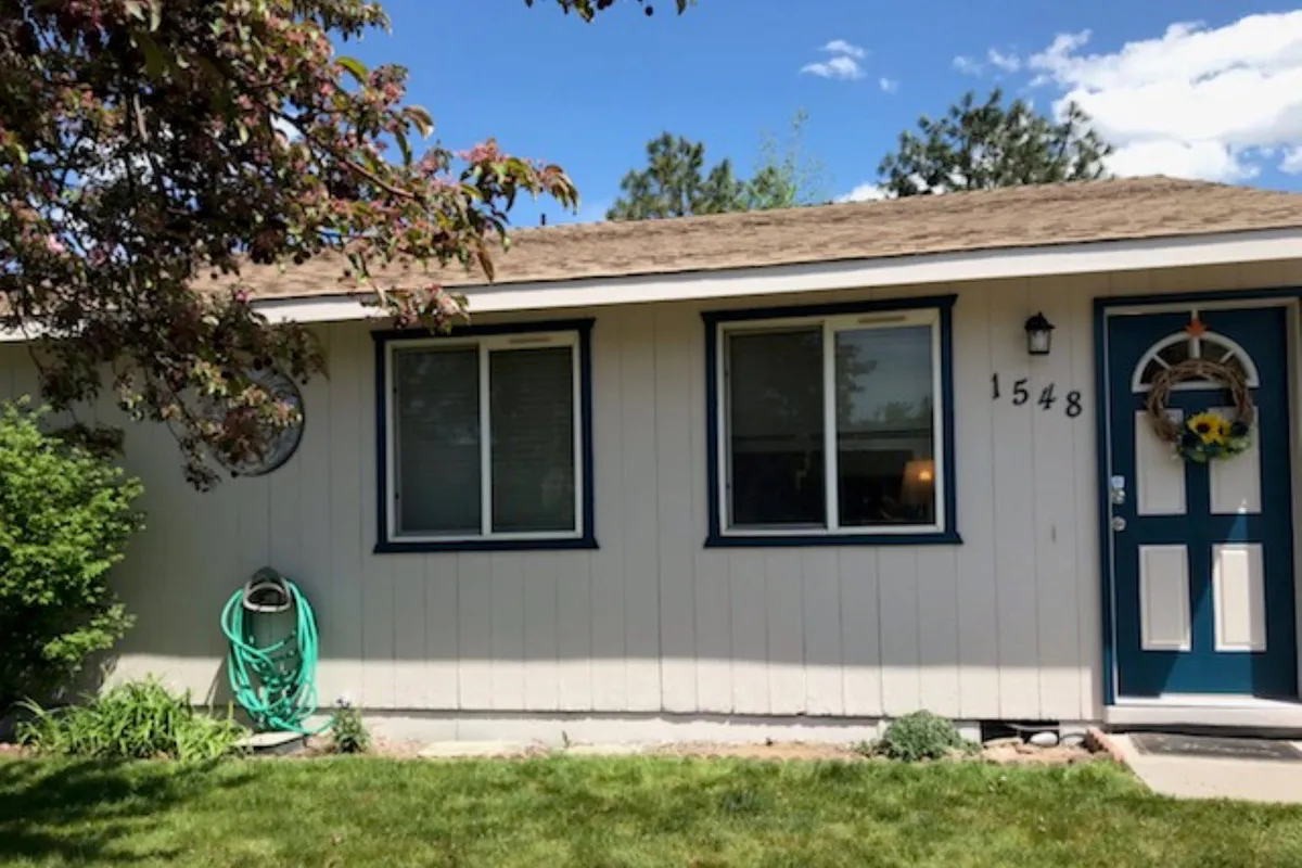An inviting front entryway with a decorative wreath on the door, flanked by windows with shutters and a green garden hose in view. The well-maintained porch and welcoming atmosphere set the tone for guests as they arrive or prepare to head out on their next outing.